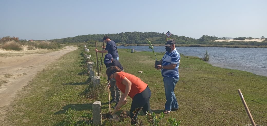 sema #Pracegover foto: na imagem há pessoas, lago, área verde, pedras e areia