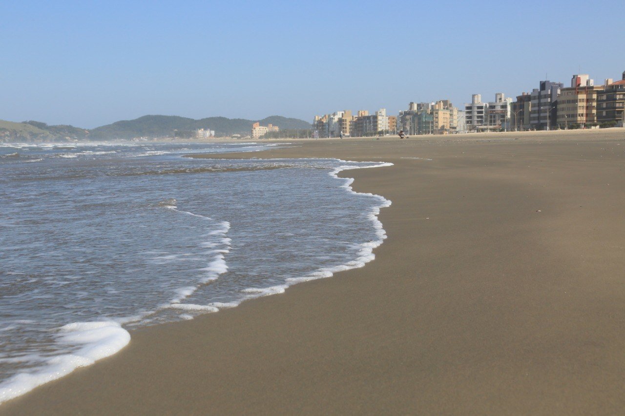 praia #Pracegover Foto: na imagem há água, areia e prédios