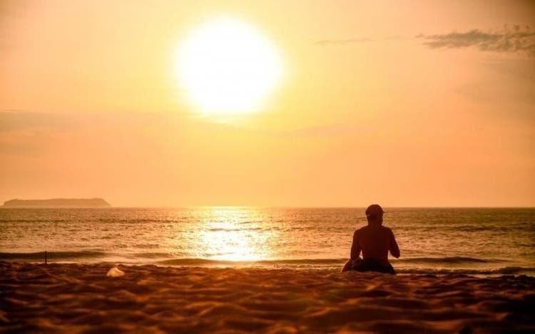verão #Pracegover Foto: na imagem há uma pessoa, areia, mar e o sol