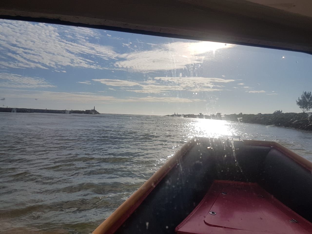 buscas #Pracegover Foto: na imagem há uma embarcação, o mar , pedras, nuvens e o céu