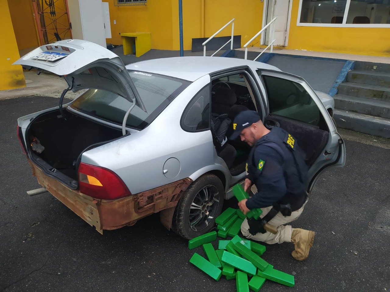 Maconha PRF #PraCegoVer Na foto, um policial retira tabletes de drogas de dentro de um carro