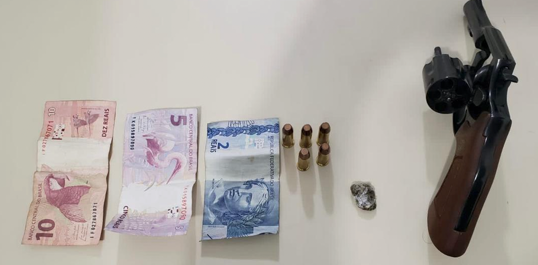 arma PM Tubarão #PraCegoVer Na foto, dinheiro, uma pequena porção de maconha, quatro munições e um revólver