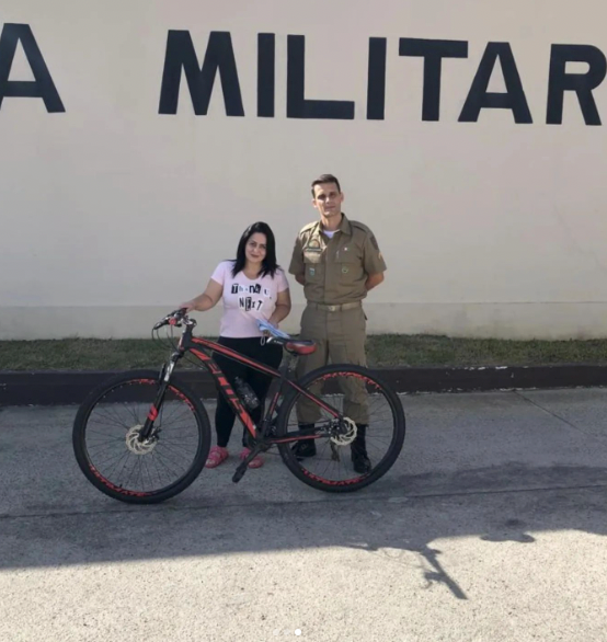 Bike PM Capivari #PraCegoVer Na foto, uma mulher segura uma bicicleta ao lado de um policial militar