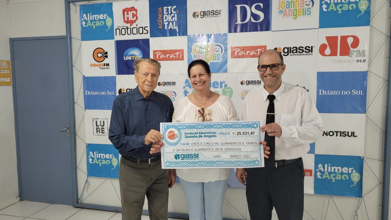 campanha #Pracegover Foto: na imagem há uma mulher e dois homens segurando um cheque simbólico