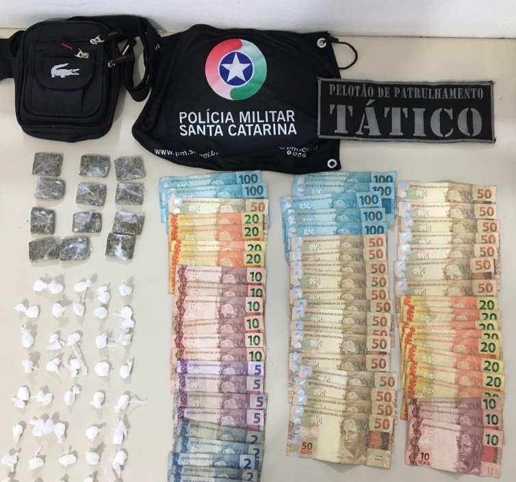 Droga Campestre #PraCegoVer Na foto, uma bandeirola com o símbolo da Polícia Militar, drogas, dinheiro e uma tarjeta com a inscrição Pelotão de Patrulhamento Tático