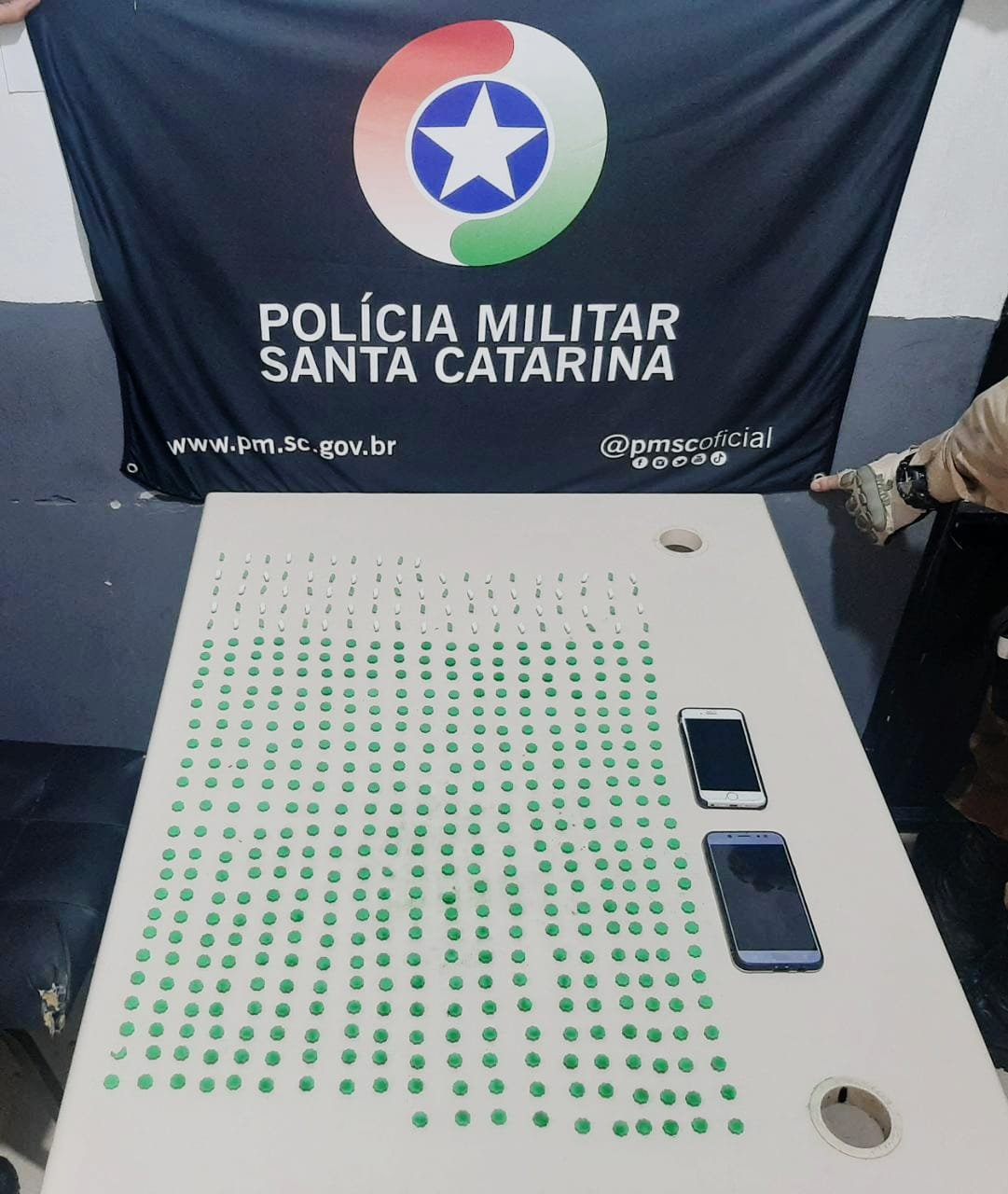 Ecstasy criciúma #PraCegoVer Na foto, Uma bandeira com o símbolo da Polícia Militar de Santa Catarina e vários comprimidos de ecstasy sobre uma mesa