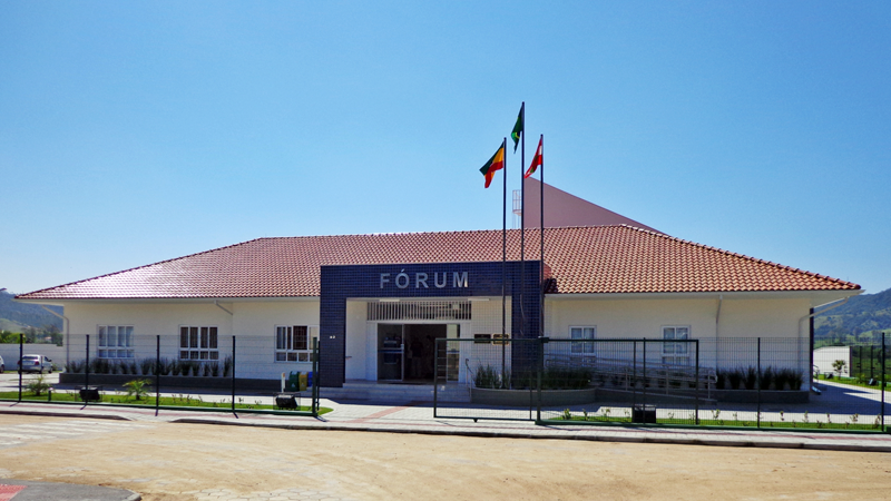 Fórum de armazem #ParaTodosVerem Na foto, a prédio onde funciona o judiciário de Armazém. O prédio é bege, com um detalhe azul na frente onde lê-se a palavra Fórum