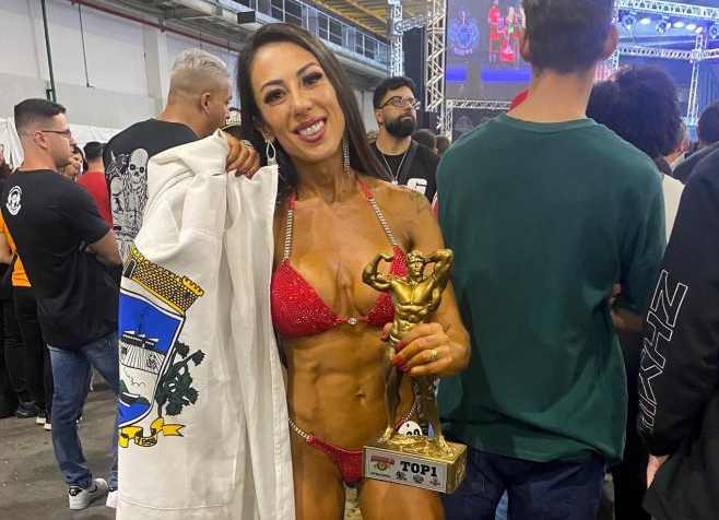 Karine Maromba1 #PraCegoVer Na foto, a atleta Karine Maromba segura o troféu de campeão no Arnold Classic 2022