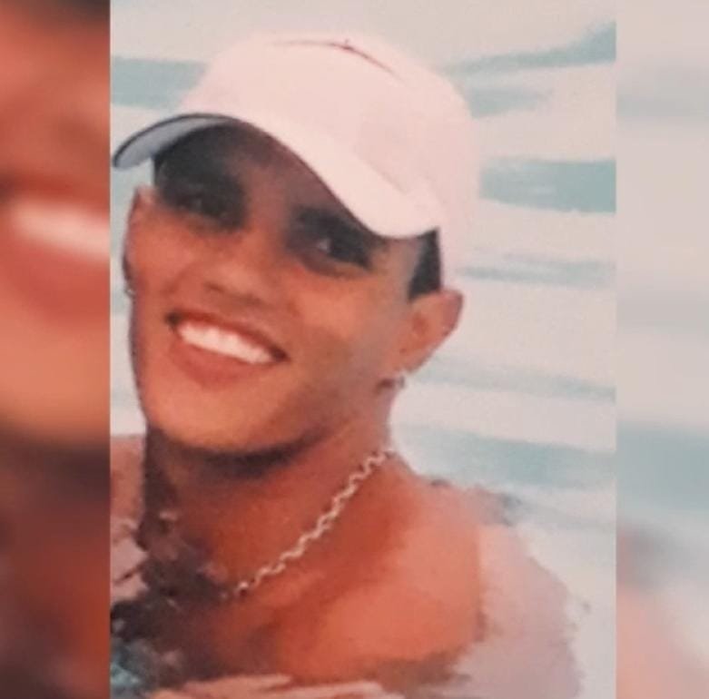Karion #PraCegoVer Na foto, um jovem moreno sorrindo. Ele tem uma corrente no pescoço e está de boné branco