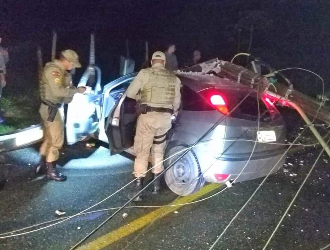 Pai bêbado #ParaTodosVerem Na foto, dois policiais militares inspecionam um carro que bateu contra um poste de energia elétrica
