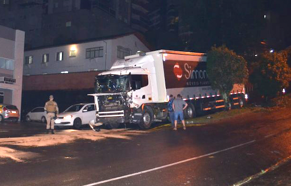 Carreta na árvore #ParaTodosVerem Na foto, um caminhão que bateu em árvores no Centro de Orleans. Há pessoas, um polícia militar e alguns outros carros na rua