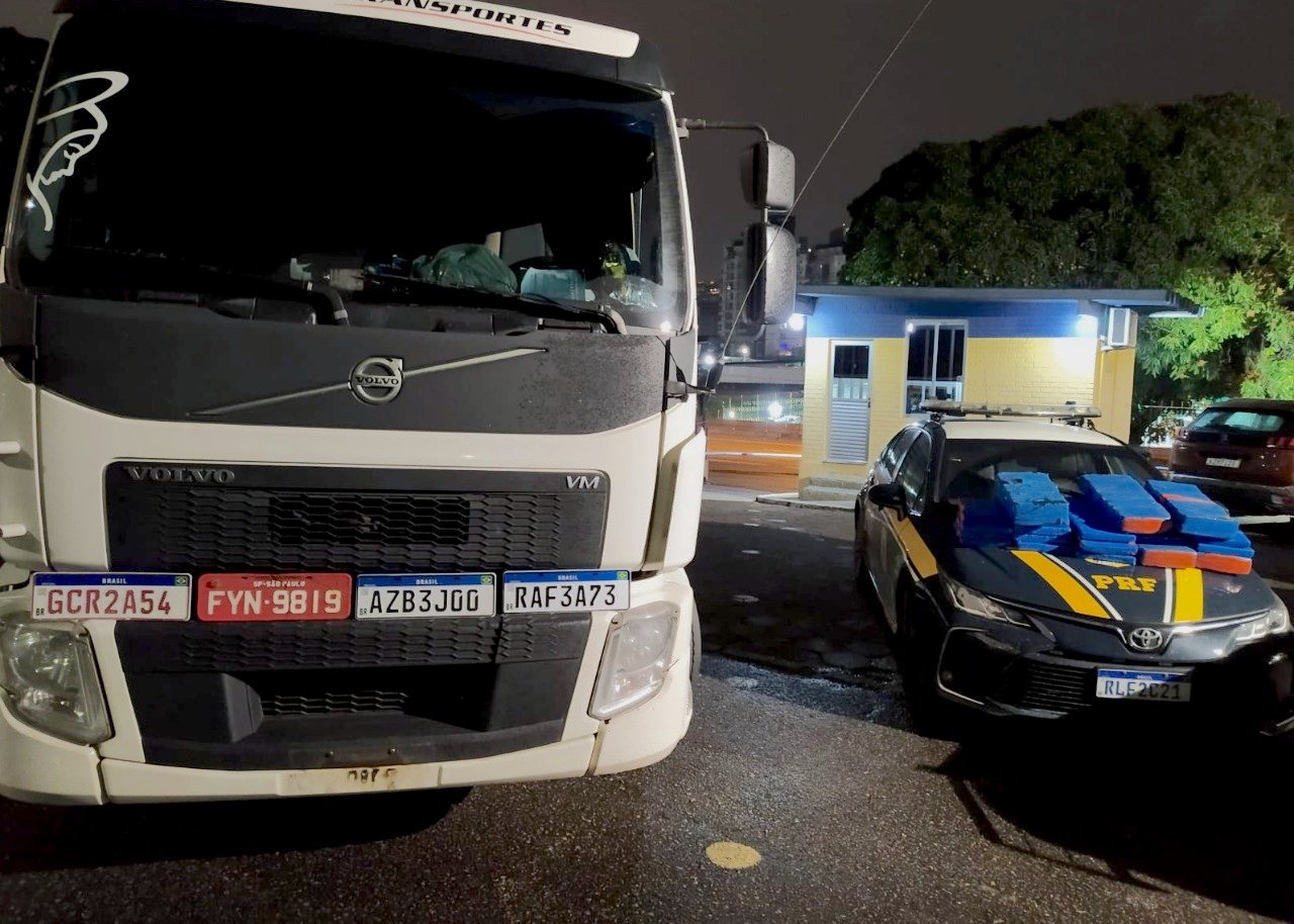 Droga esgoto PRF 2 #ParaTodosVerem Na foto, um caminhão branco, quatro placas clonadas e uma viatura da Polícia Rodoviária Federal (PRF) com os tabletes de maconha encontrados dentro do veículo