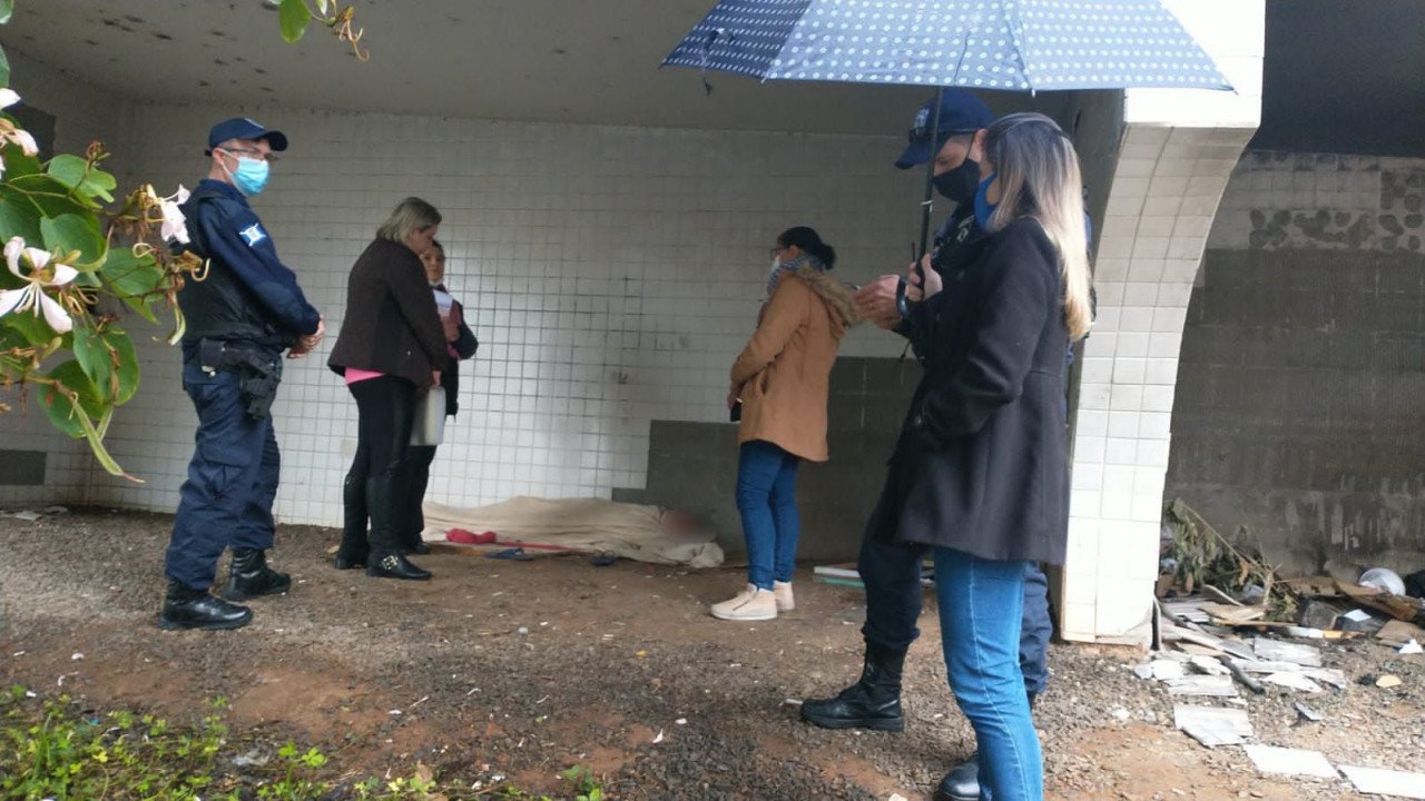 GMT #ParaTodosVerem Na foto, um menor de idade está deitado no chão, em um dos vãos do Centro Municipal de Cultura de Tubarão. Guardas municipais e profissionais da Fundação Municipal de Desenvolvimento Social estão a sua volta
