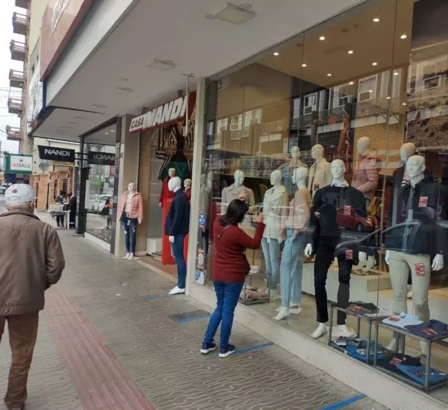 Comércio TB #ParaTodosVerem Na foto, uma mulher olha produtos em uma vitrine