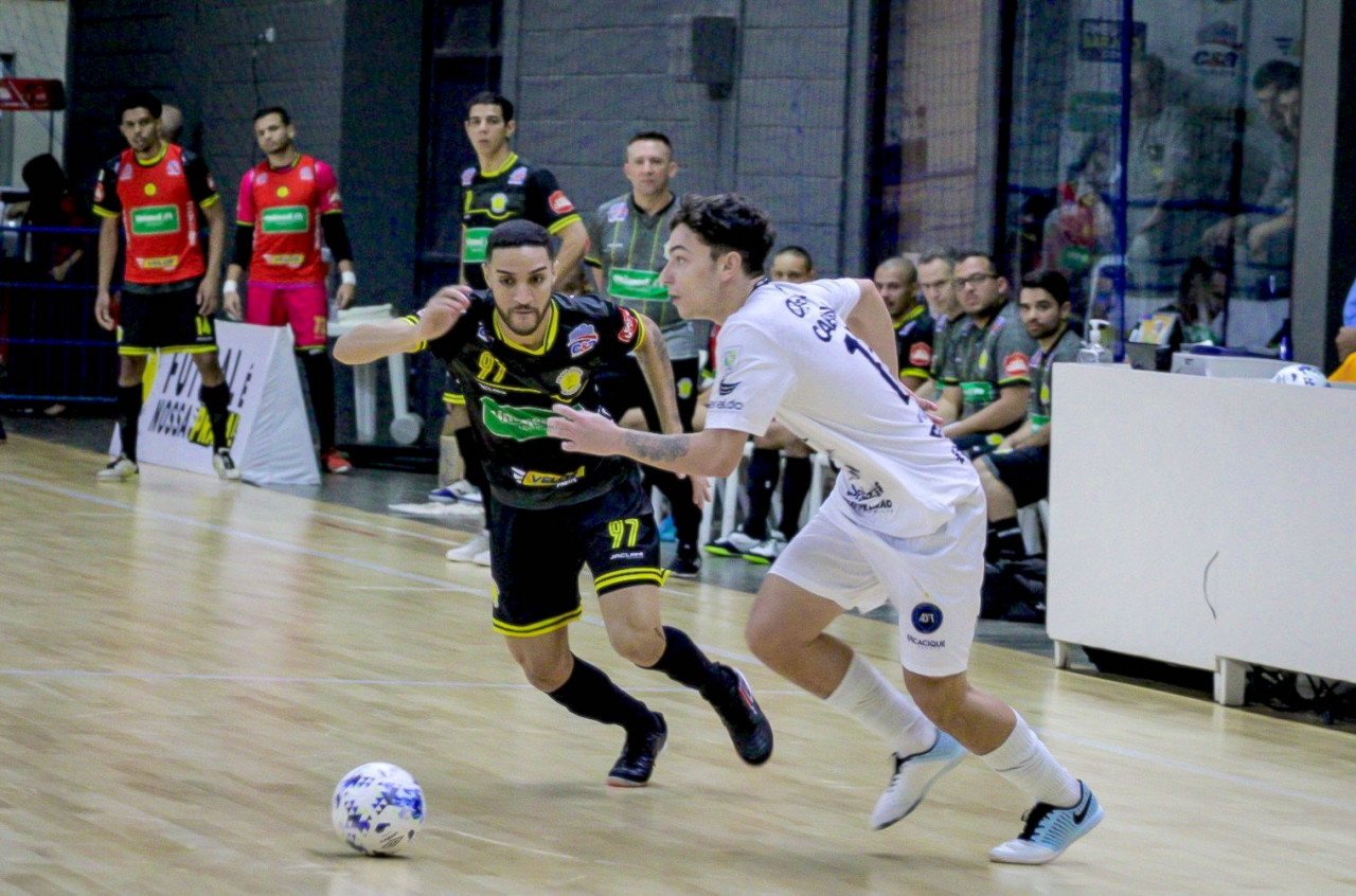 da5425ce-d38f-4229-b87b-0a62efa9151e #ParaTodosVerem Na foto, dois jogadores de futsal disputam a posse de bola