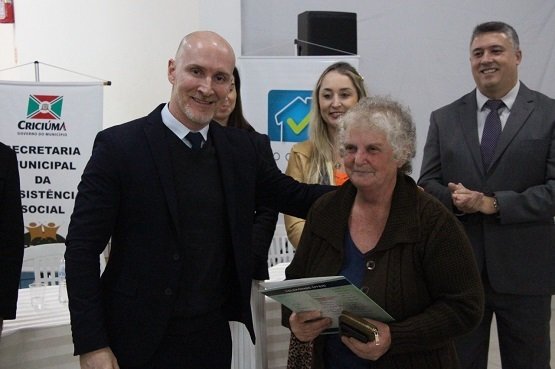 lar 5 (1) #ParaTodosVerem Na foto, uma senhora recebe a escritura de seu imóvel