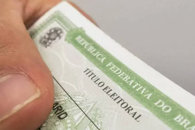 Titulo eleitor #ParaTodosVerem Na foto, uma pessoa seguro o seu título de eleitor