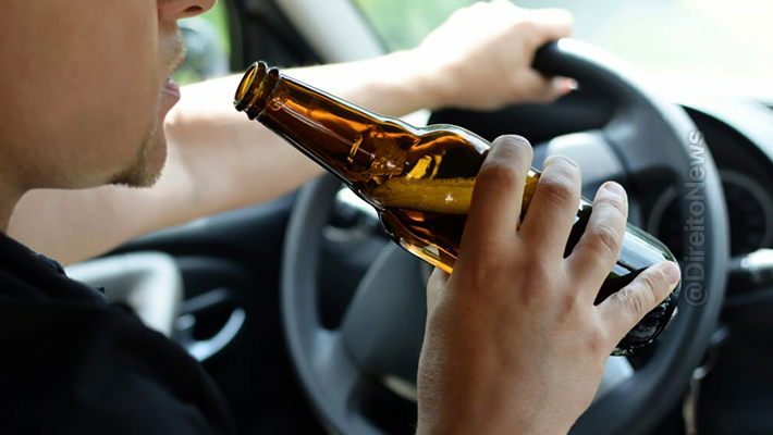 STJ Embriaguez Foto mostra condutor ao volante segurando garrafa longneck de cerveja