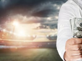 Close-up of a man's hand holding US dollars against the background of the stadium. The concept of sports betting, making a profit from betting, gambling. American football